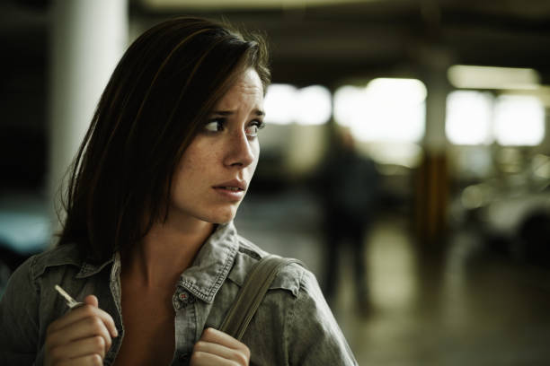 A terrified young woman in an underground parking garage being followed by a sinister man