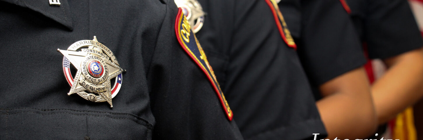 Deputies lined up with closest deputy having a badge front and center. the word "Integrity" is in the bottom right hand corner